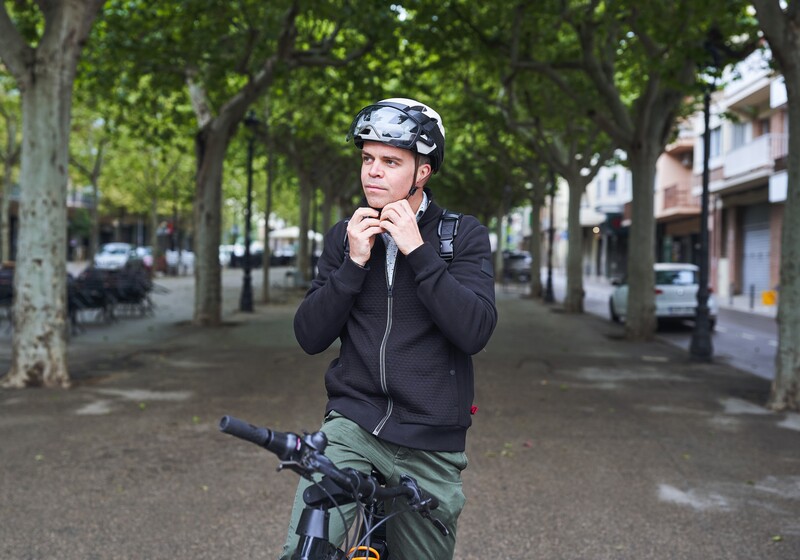 Un cycliste accroche son casque avant de rouler.